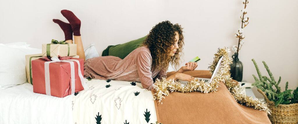 Woman in a christmas decorated bedroom making a payment on her laptop